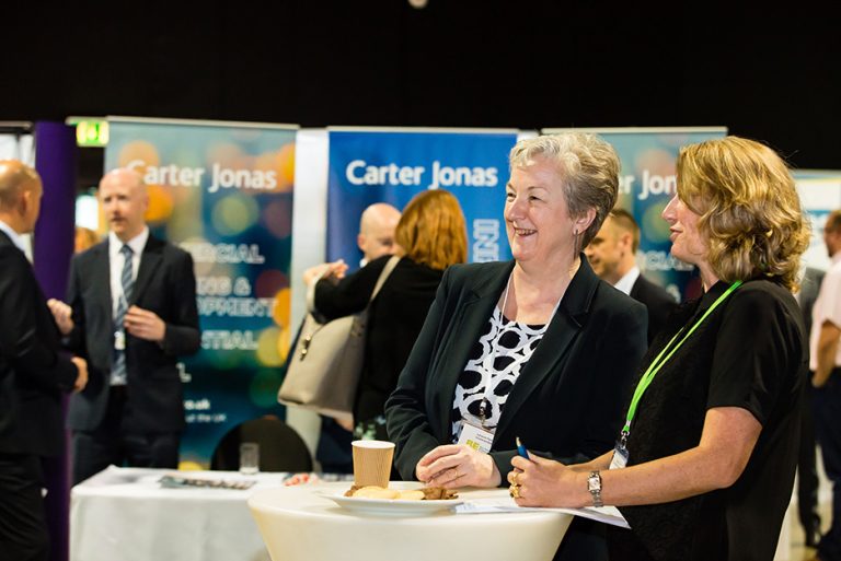 Carter Jonas Exhibition stand with Attendees talking at West Yorkshire Economic Growth Conference 2018